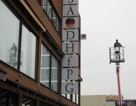 Vertikales an eine Fassade angebrachtes Schild für die Deutsche Hochschule für Prävention und Gesundheitsmanagement