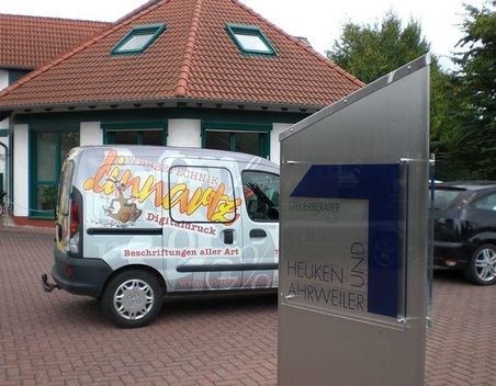 Ein Lieferwagen mit bunter Werbung hinter einem Metallschild