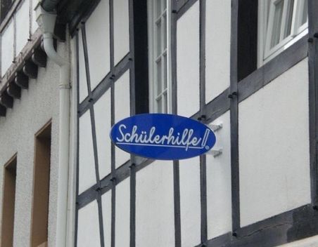 Blaues Schülerhilfe-Schild an einer Fachwerkhaus-Fassade