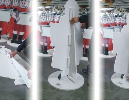 Eine Person, die einen großen Kartonausschnitt in einer Folge von drei Bildern zusammensetzt